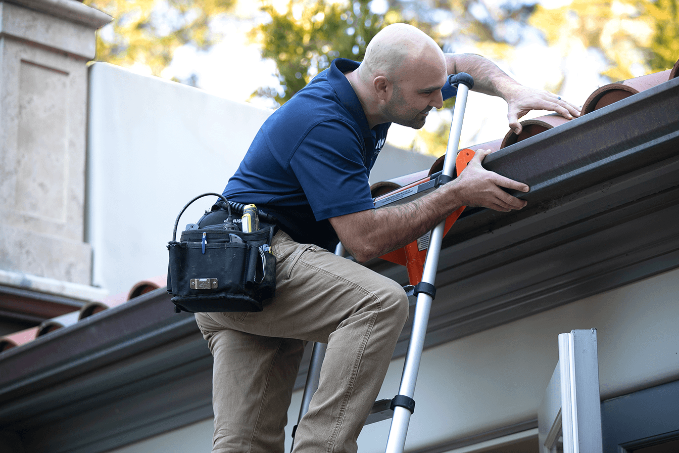 WIN Home Inspector conducting a roof inspection from a ladder.
